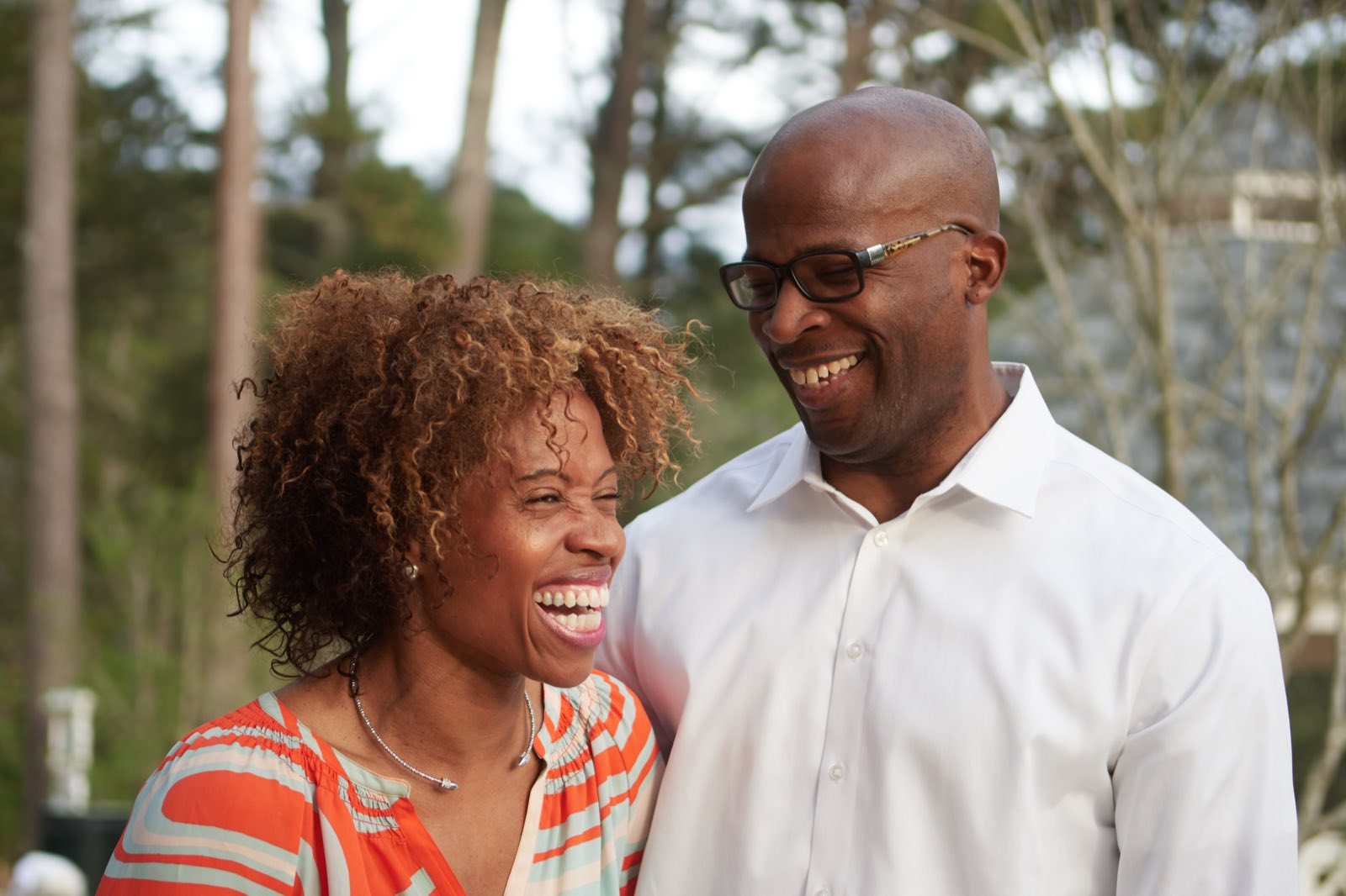 The parents laughing together outdoors.