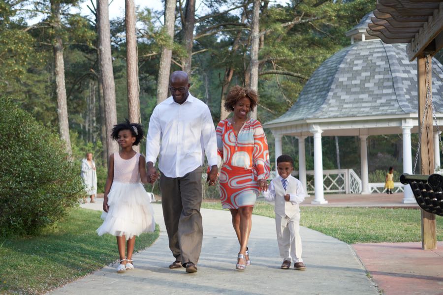A family of four walking a park path together in spring light.