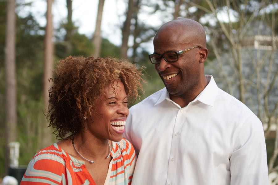 The parents laughing together outdoors.