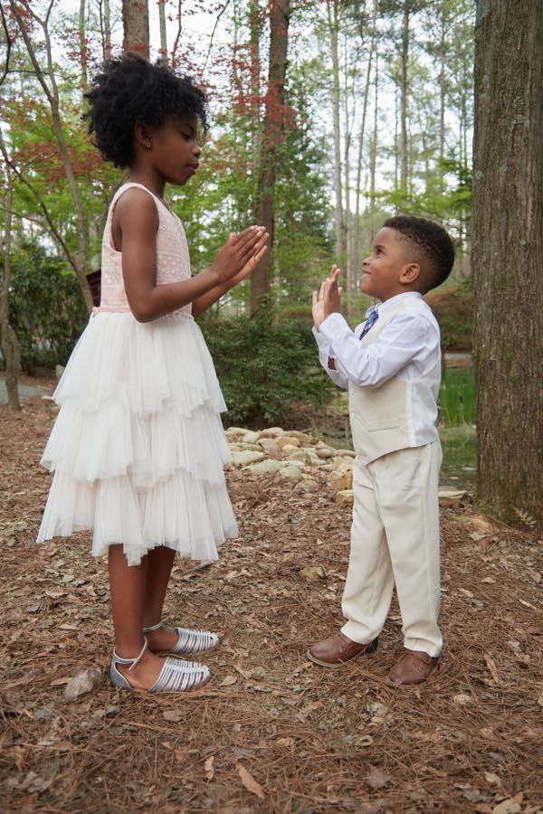 The two children facing each other on a wooded path.