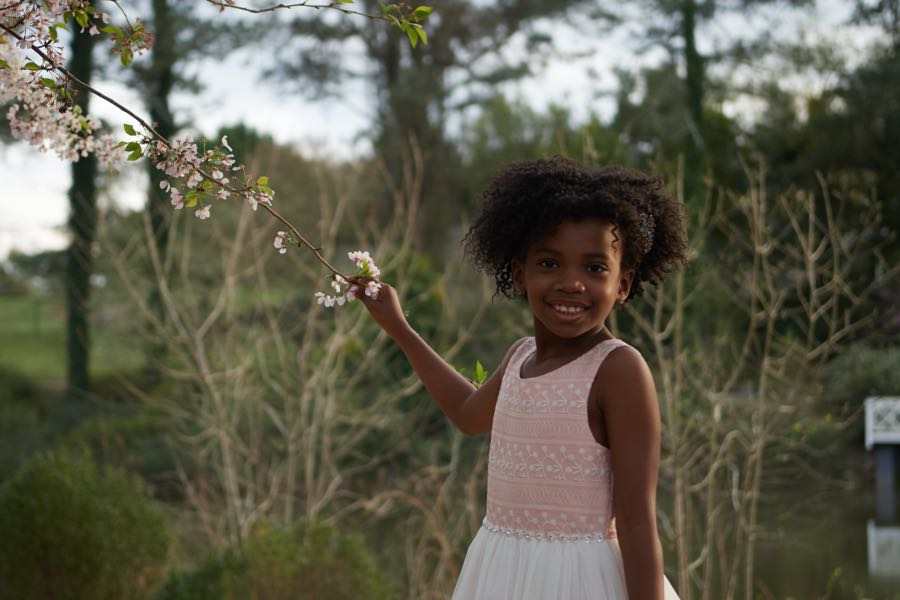 A girl holding a single bloom up to the light.