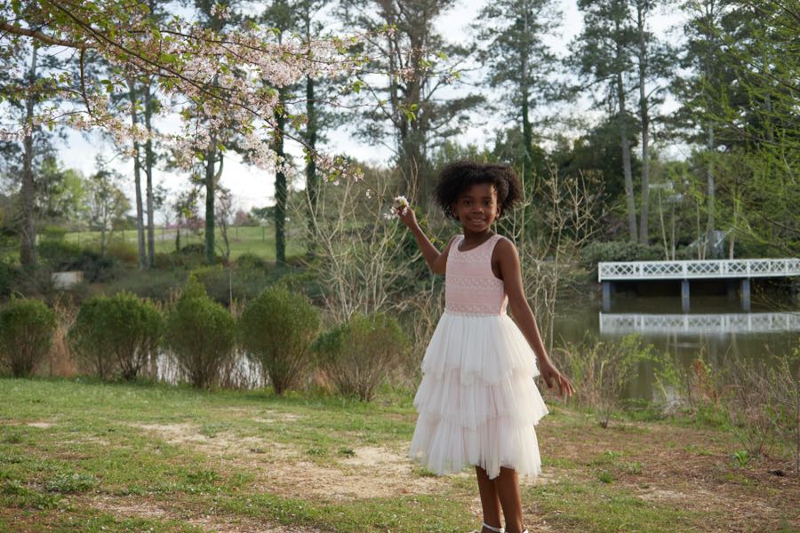 A girl in a white dress walking through an open field.