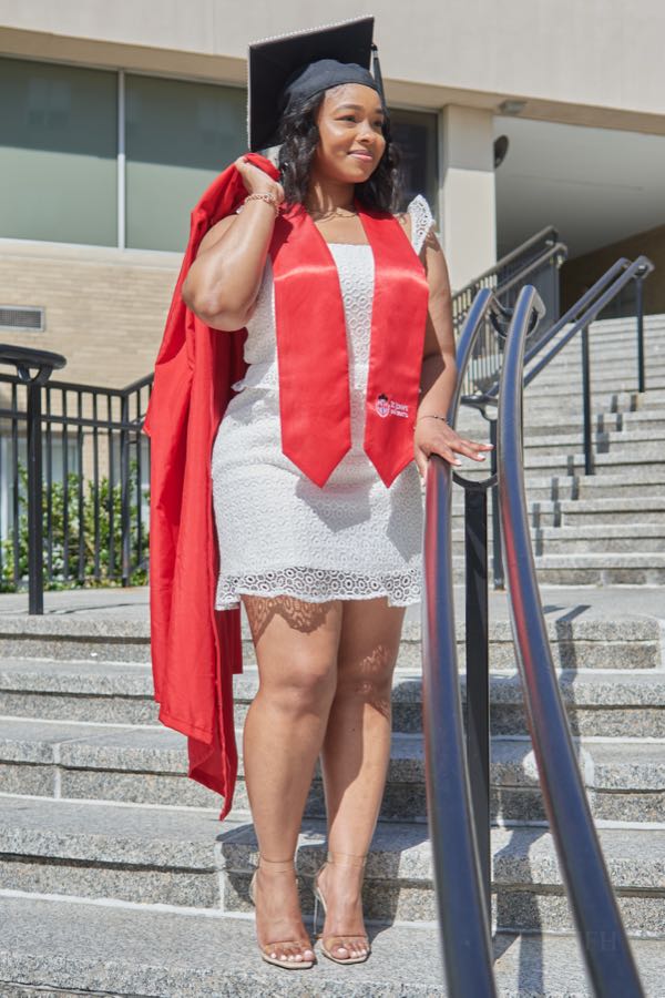 Walking down the campus steps in a red graduation gown.