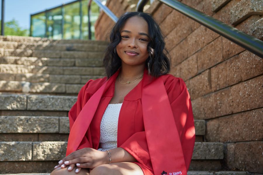 Seated on the campus steps in the gown.