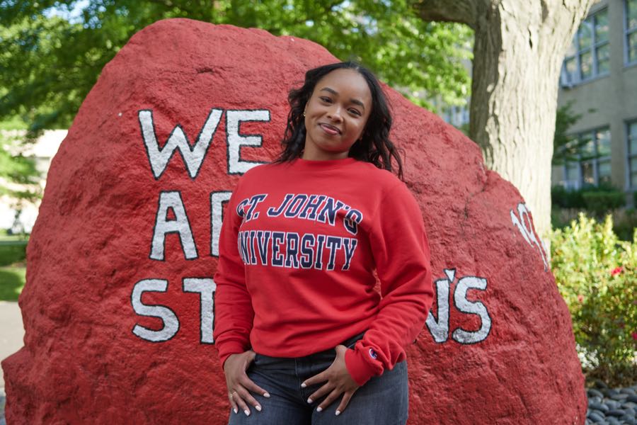Standing at the painted campus rock in a university sweatshirt.