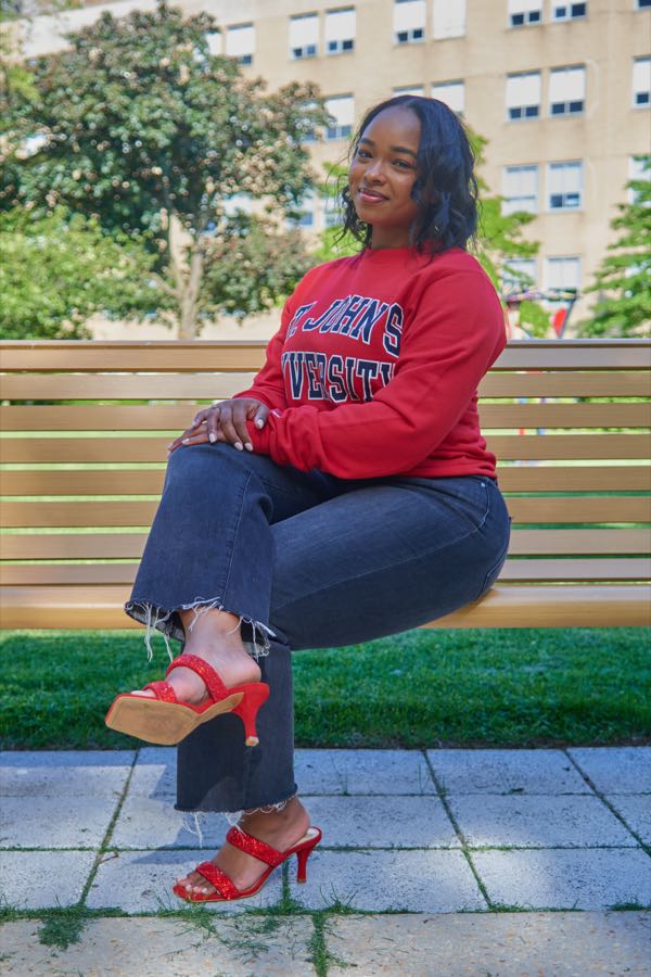 Laughing on the bench, legs crossed.